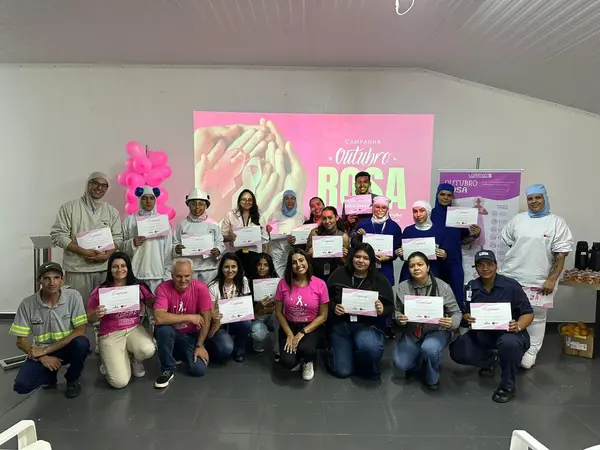 Equipe e colaboradores exibindo certificados de participação no Outubro Rosa, com a projeção da campanha ao fundo.