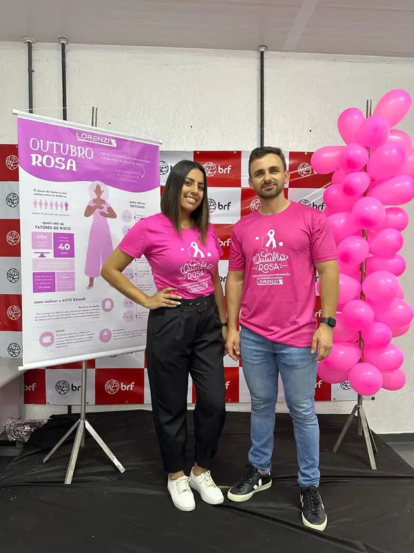 Integrantes da equipe Lorenzi com camisetas do Outubro Rosa ao lado do banner informativo, na unidade da BRF em Jataí.